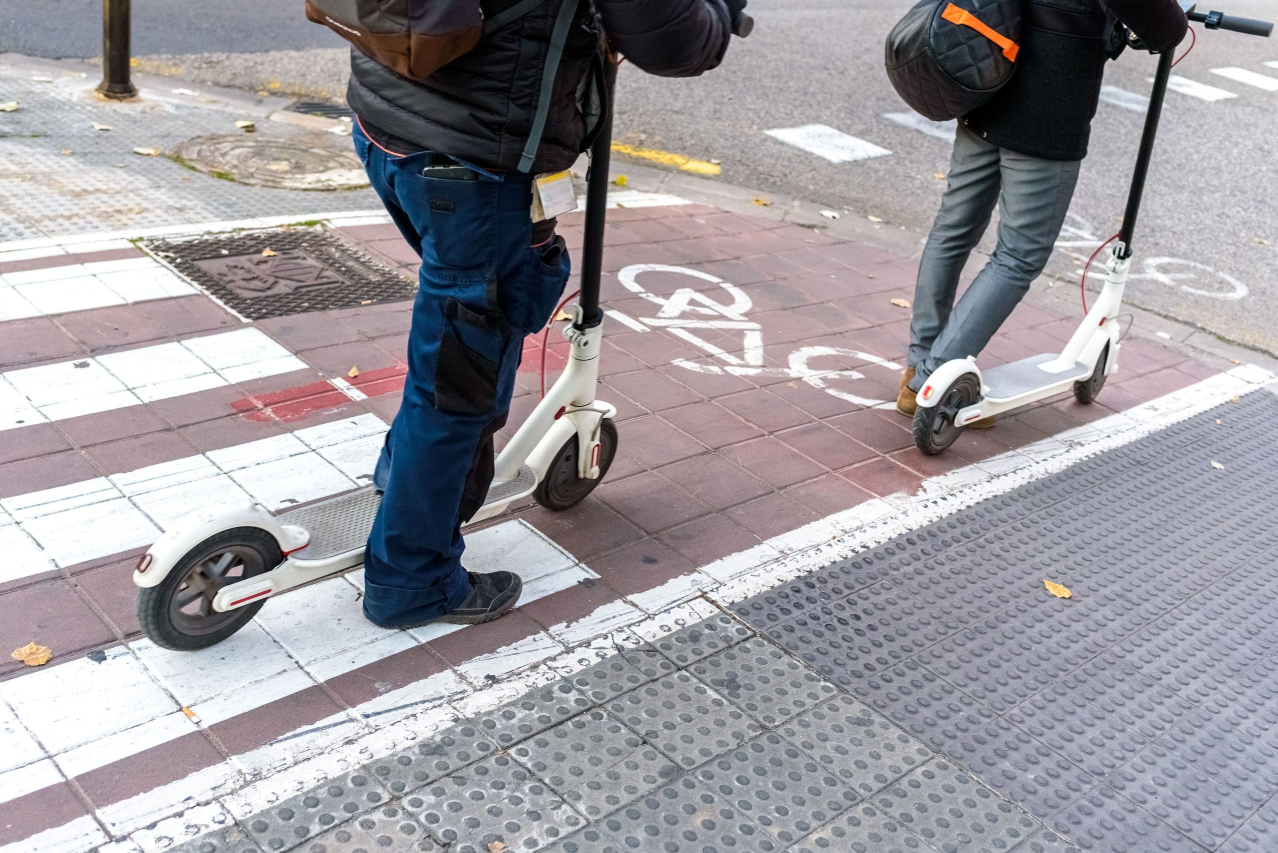 dos personas en patinete por el carril de bicicletas